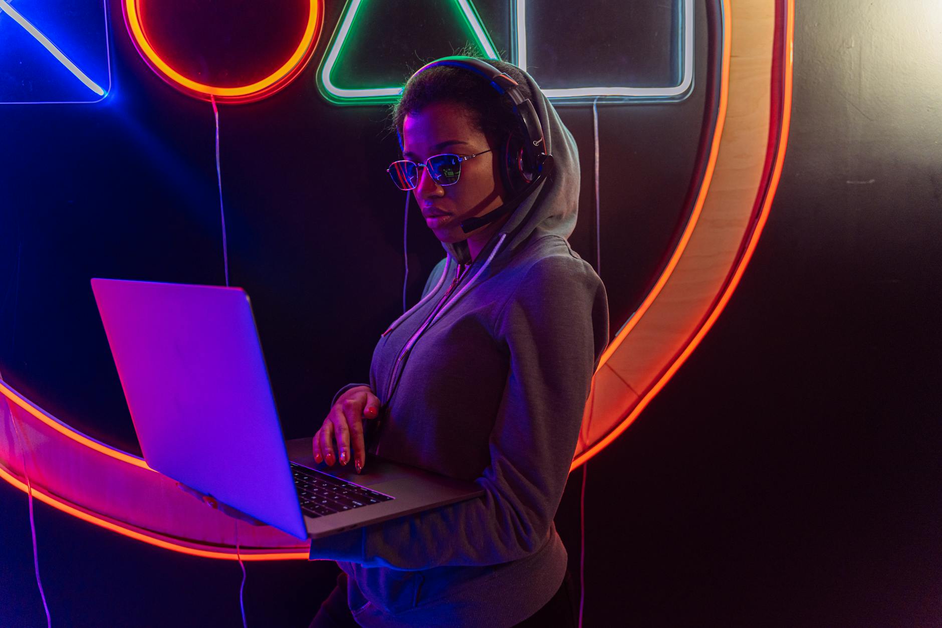 woman in hoodie working on a laptop while wearing blue light filter glasses showcasing the benefits of using them.