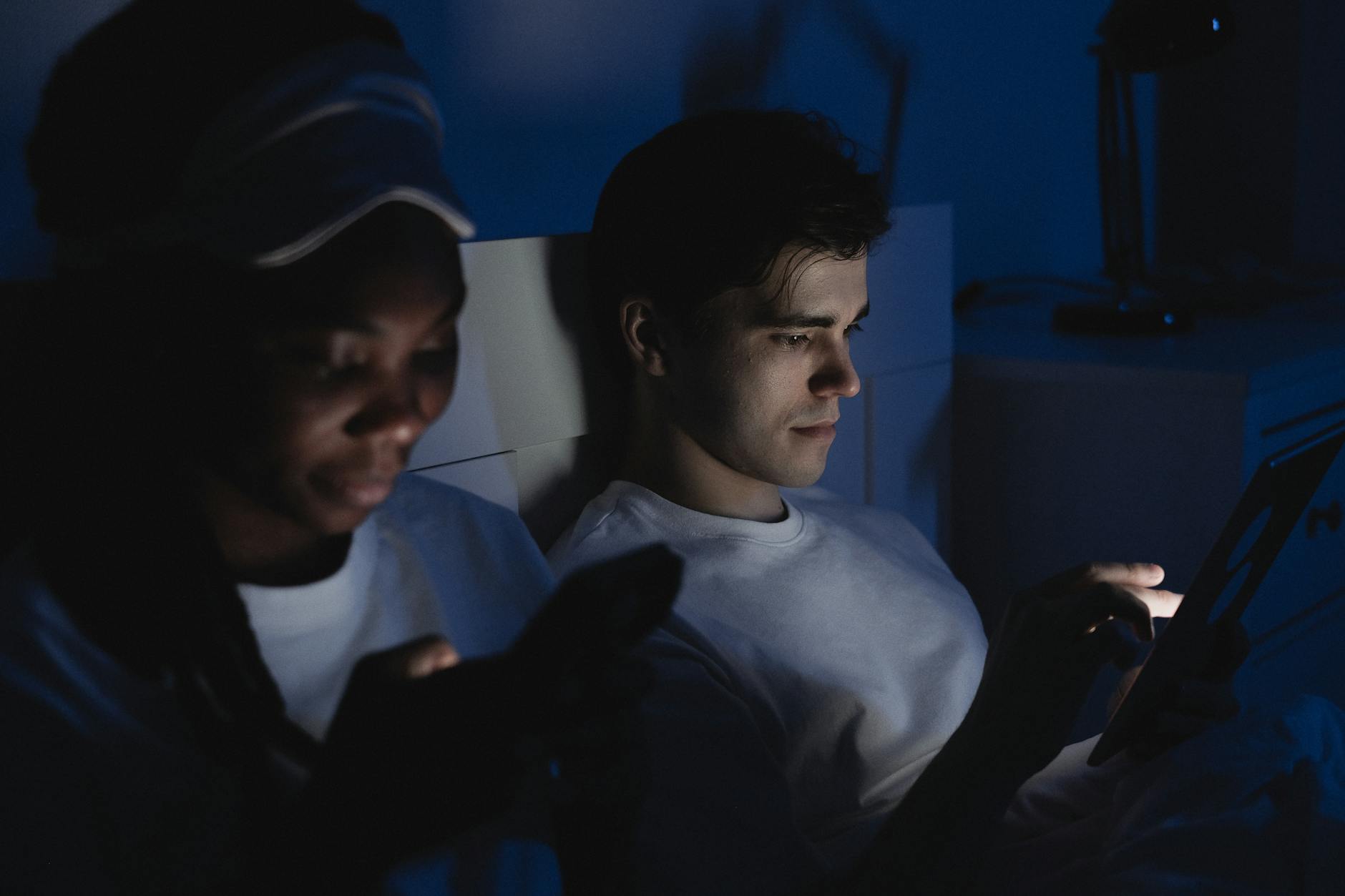 man and woman using mobile phone in the dark showcasing the blue light disrupts sleep. They need blue light blocking glasses, it helps to block light and get better sleep.