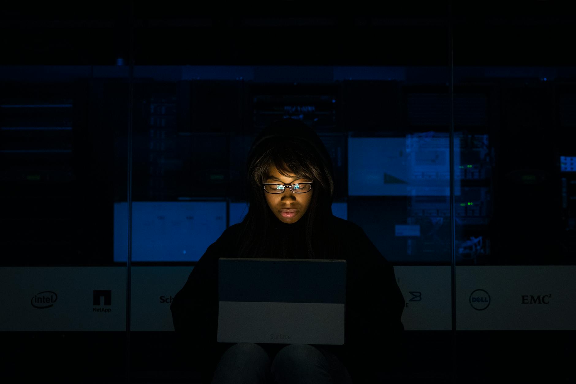 woman wearing blue light protection glasses while working on a laptop showcasing the best combination for eye protection is to use both glasses and night mode on digital screens.