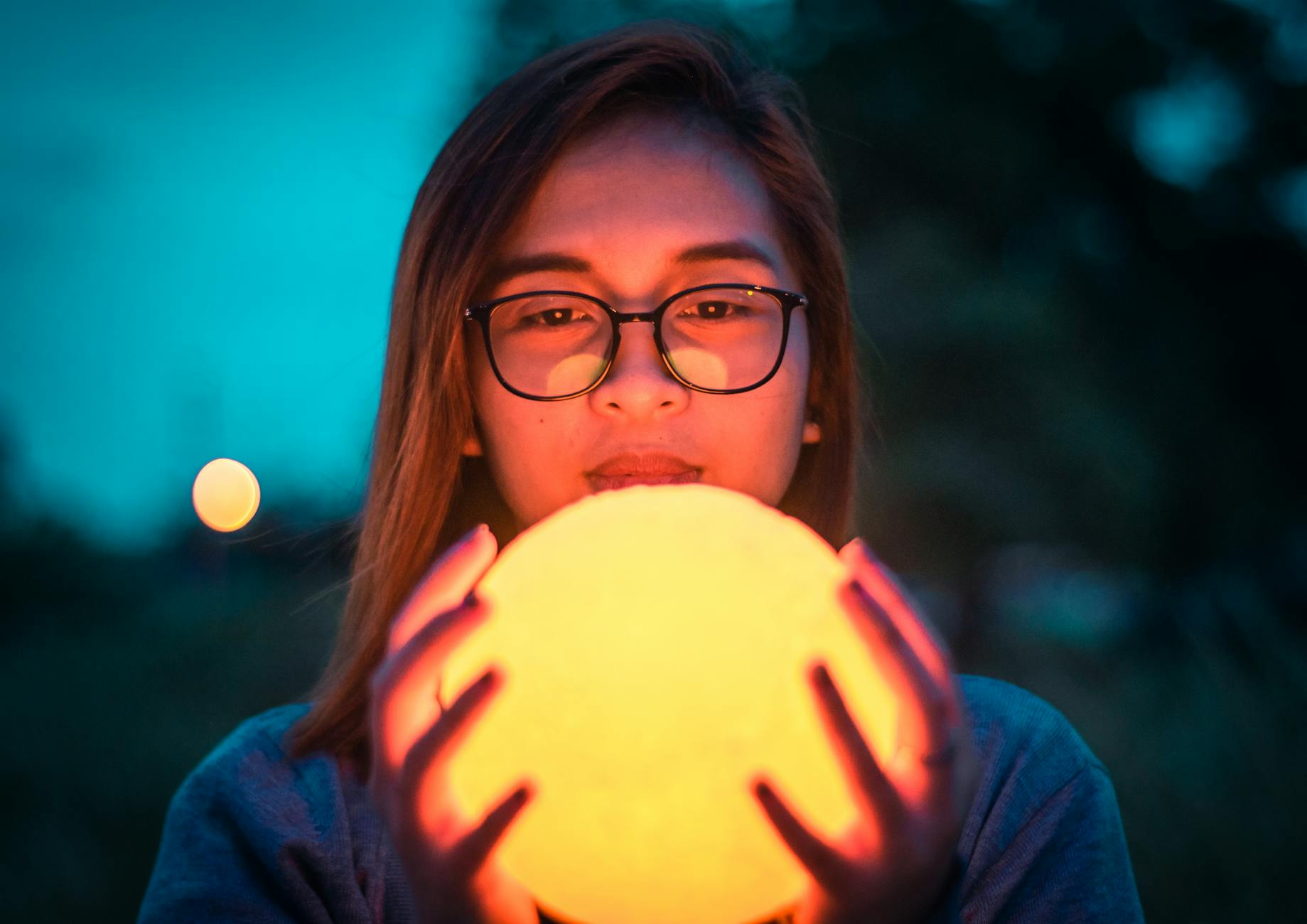 woman in black framed eyeglasses holding a round lamp